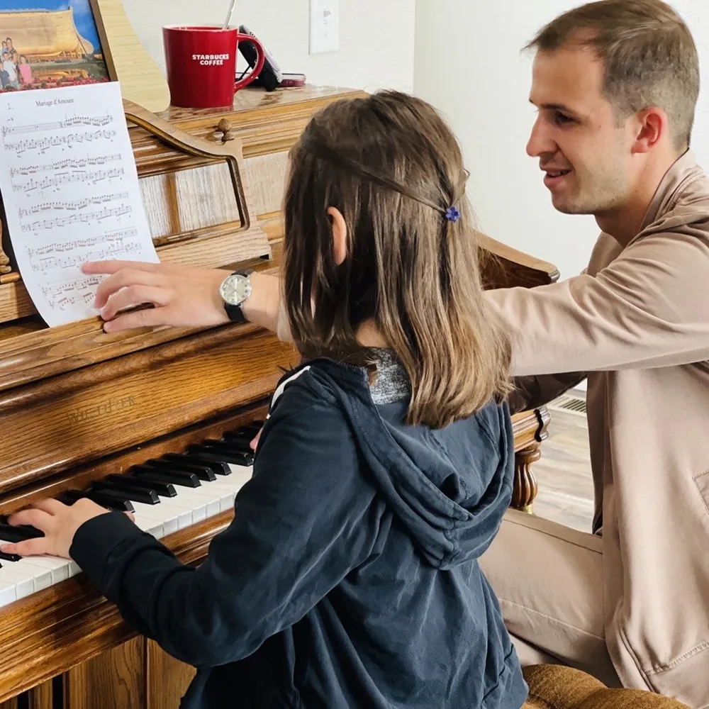 Aleksandr Savchenko showing a score to a young student at the piano