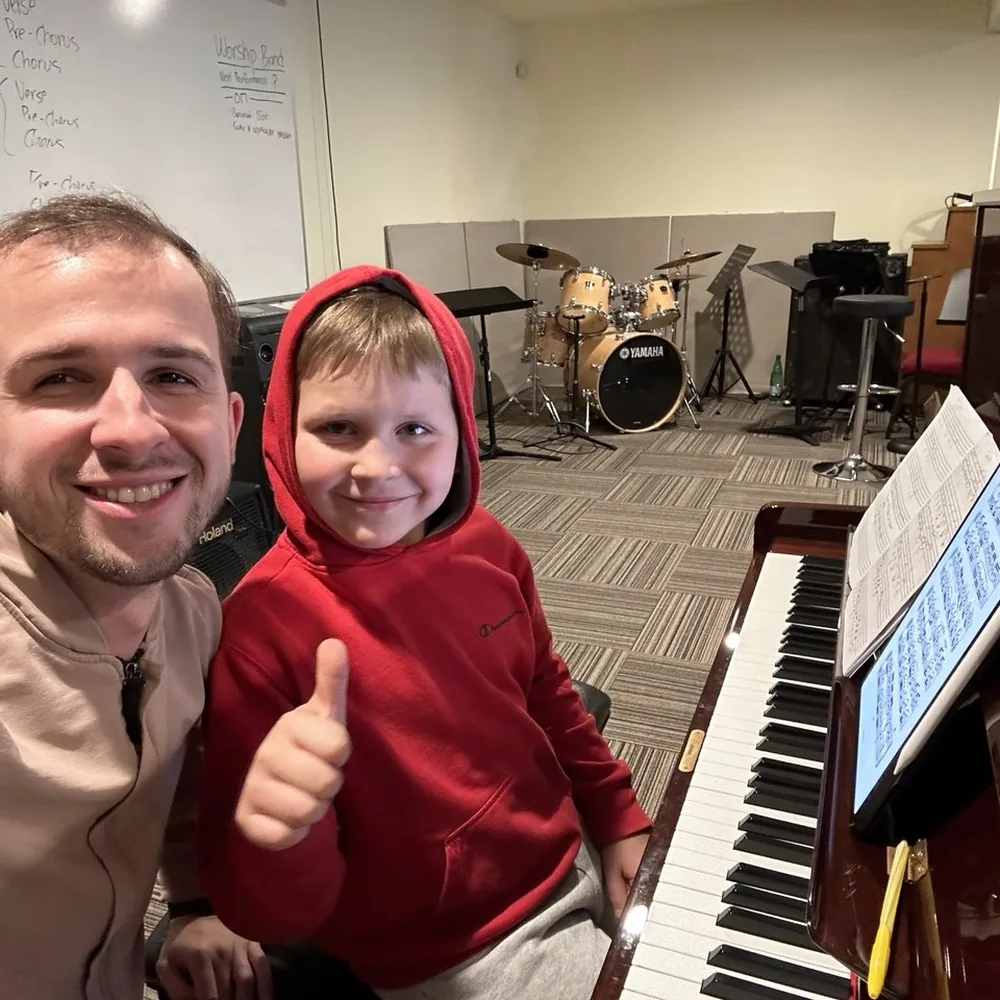 A young beginner at the keyboard with his teacher