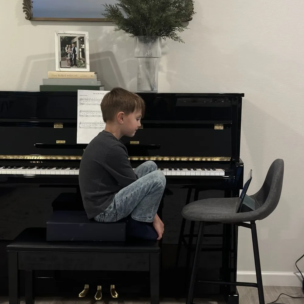 A boy practising at an upright piano in the studio