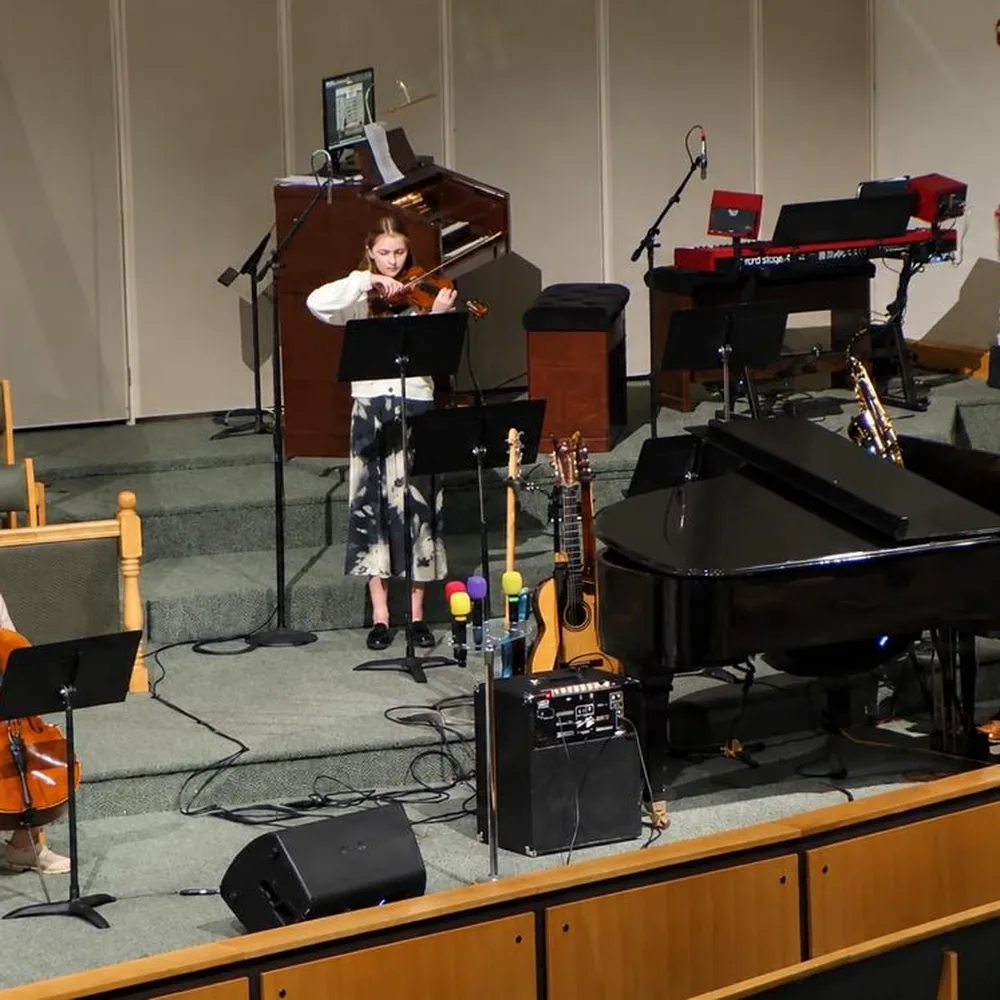 Students performing on stage with violin and grand piano