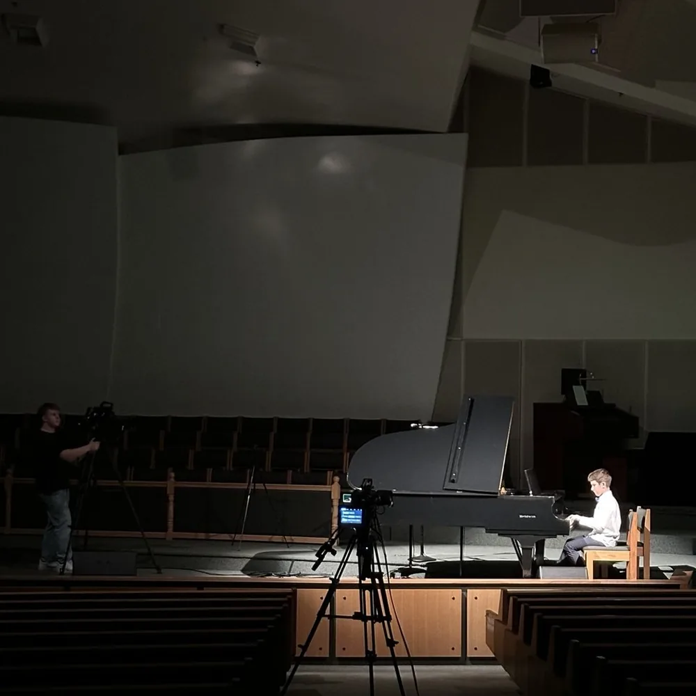 A student rehearsing on the grand piano in an empty hall