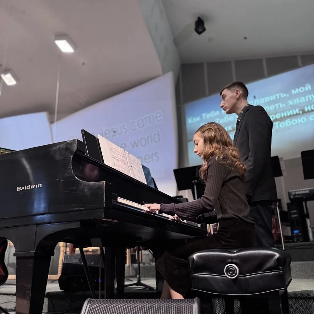A student playing the grand piano during a church service